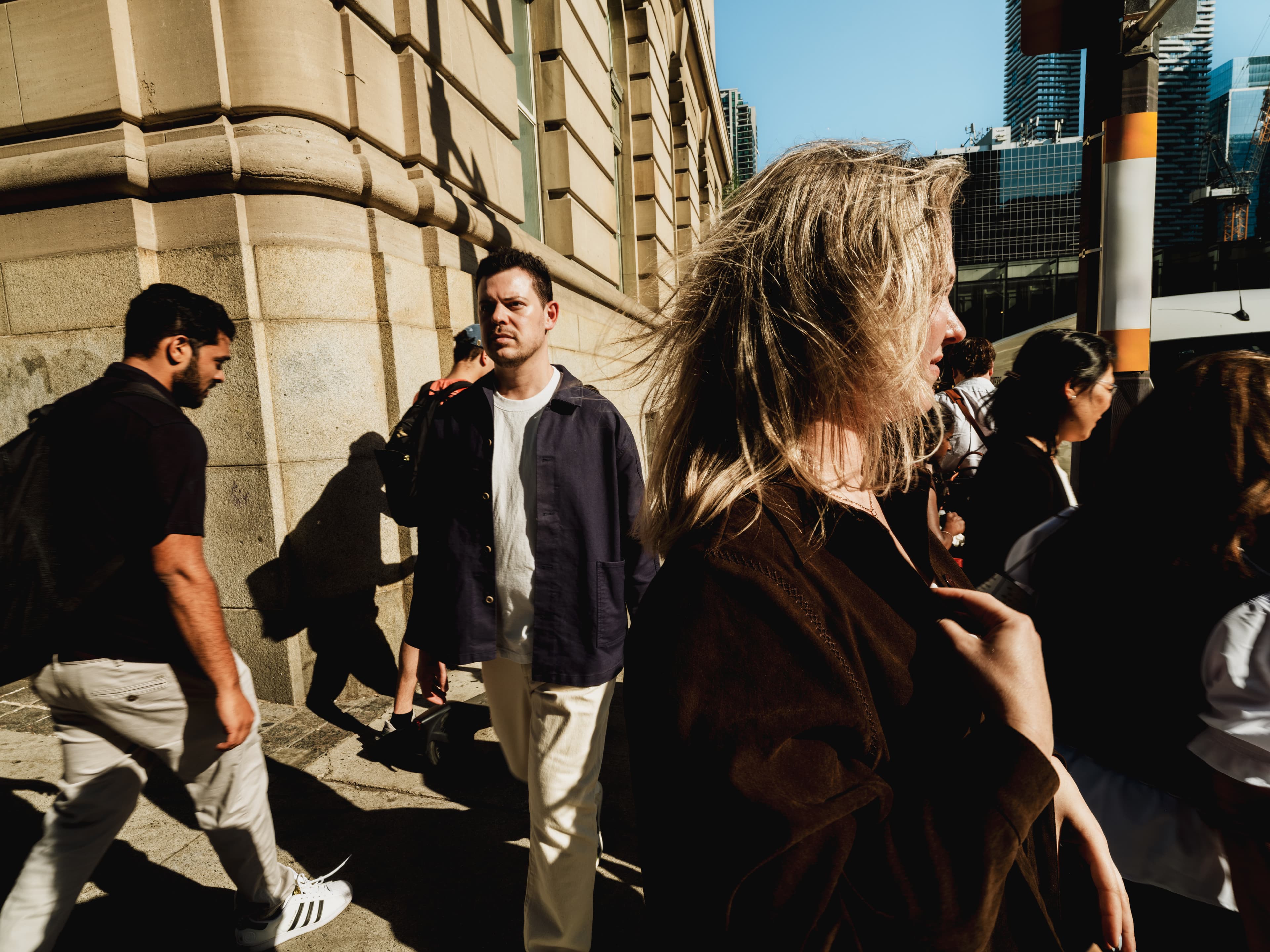 Close wide shot of a man walking through a crowd waiting to cross at a busy city intersection