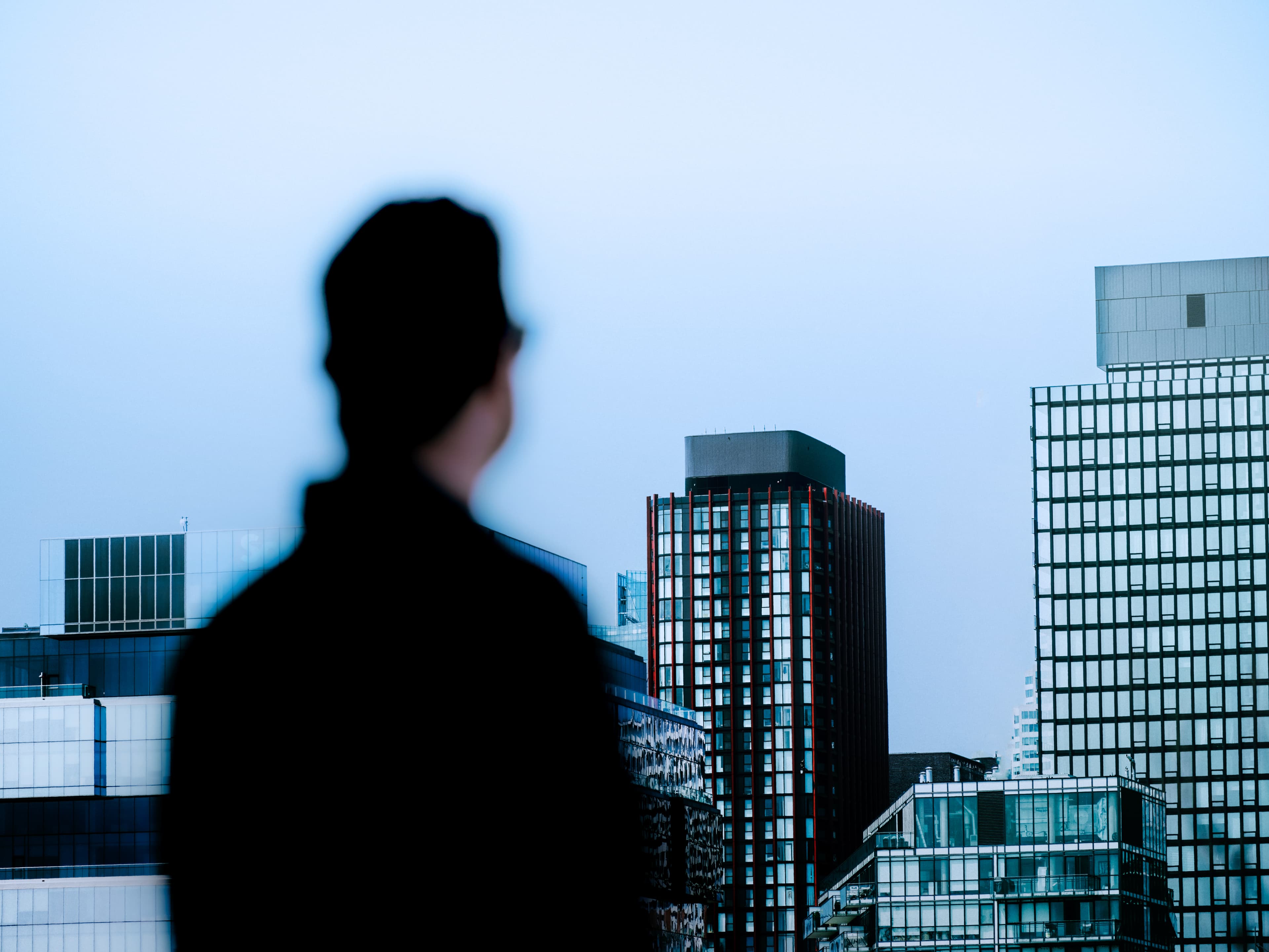 A man stands out of focus looking towards a city skyline